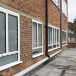 Commercial white windows installed by First Windows with drainpipes